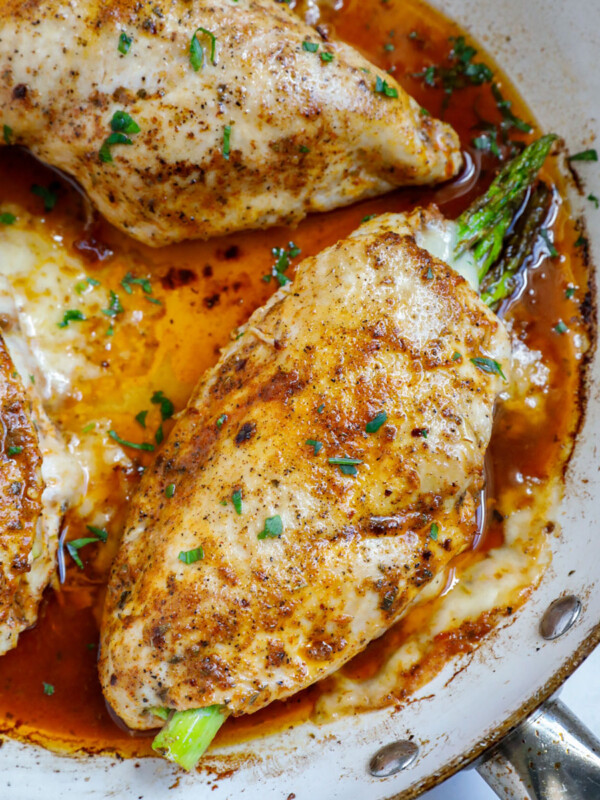 Top down shot of asparagus stuffed chicken breasts in a skillet.