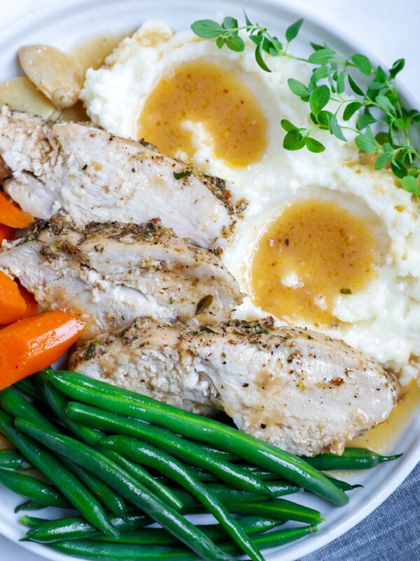 close up of sliced turkey breasts on a plate with sides