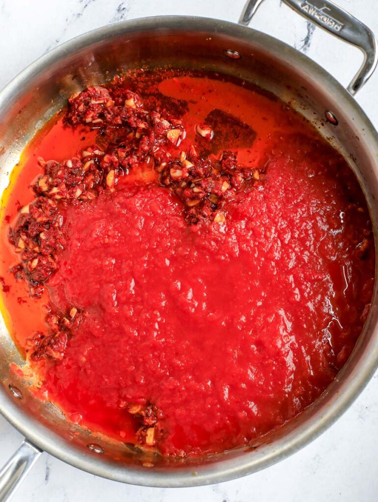 Adding tomato sauce to pot.