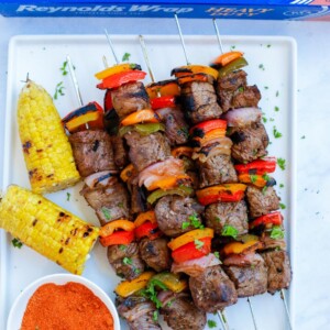 Grilled beef kebobs on a white plate