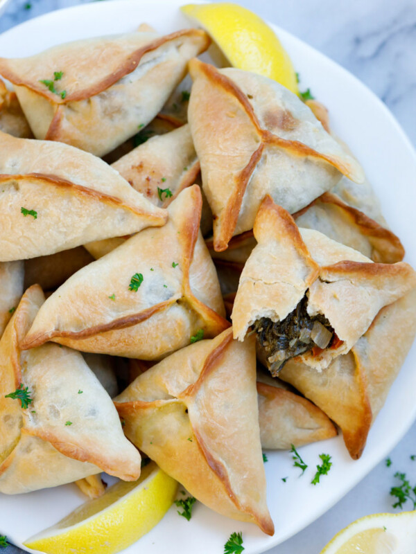 Baked lebanese spinach pies served on a plate with lemon wedges