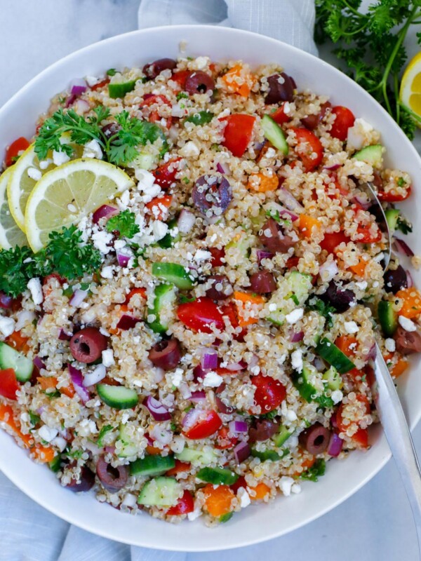 mediterranean quinoa salad served in a dish, dopped with feta cheese and lemon wedges