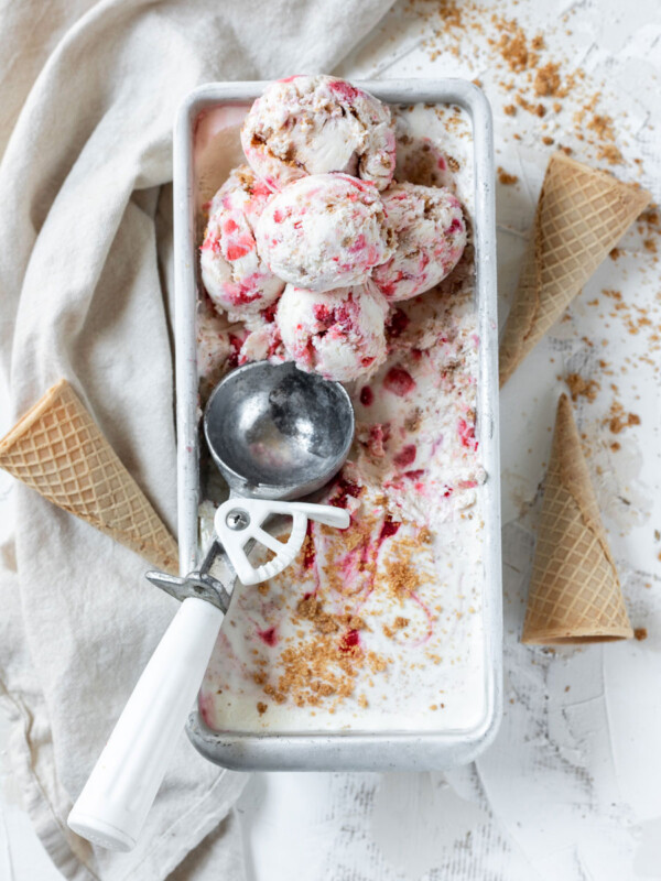 strawberry cheesecake ice cream in a pan with scoops of ice cream