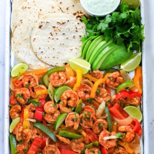shrimp fajita in a sheet pan with tortilla, avocado and dressing