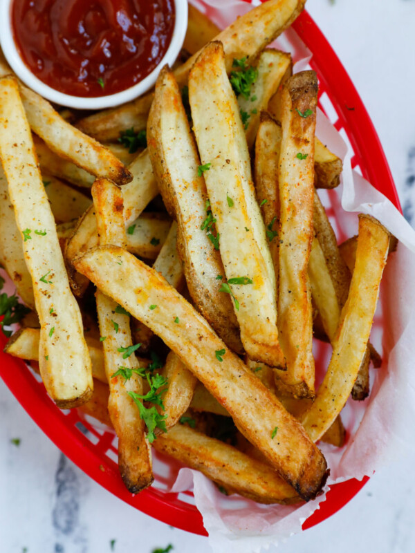 Close up of a basket of french fries with ketchup on the side.