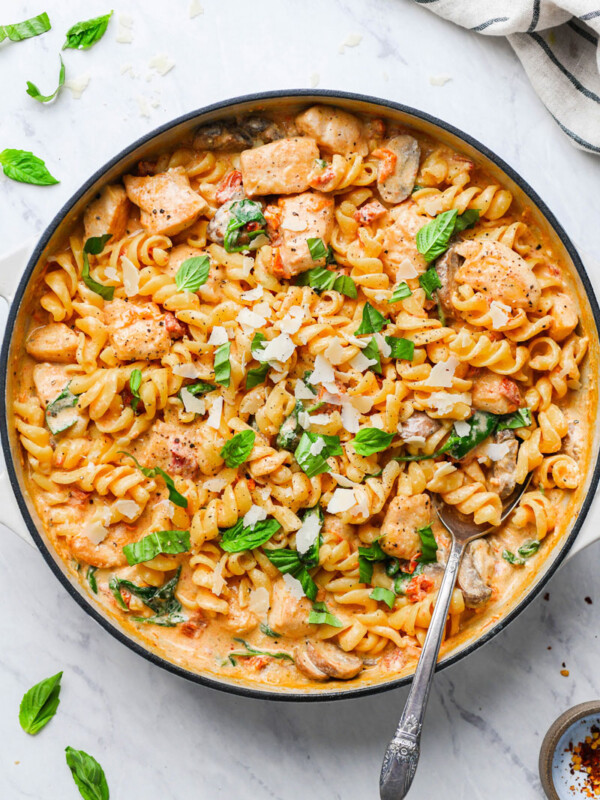 creamy mushroom chicken pasta in a skillet garnished with basil