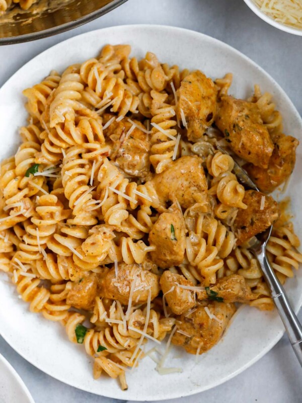 A bowl of creamy cajun chicken pasta with a fork inside.