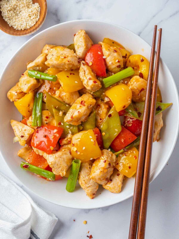 A plate of Szechuan chicken with chopsticks on the side.