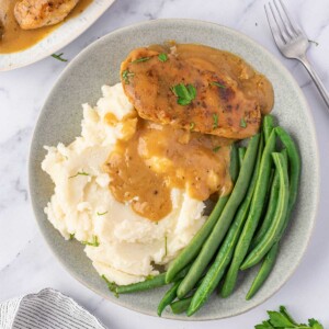 A plate of chicken, gravy, mashed potatoes, and green beans.
