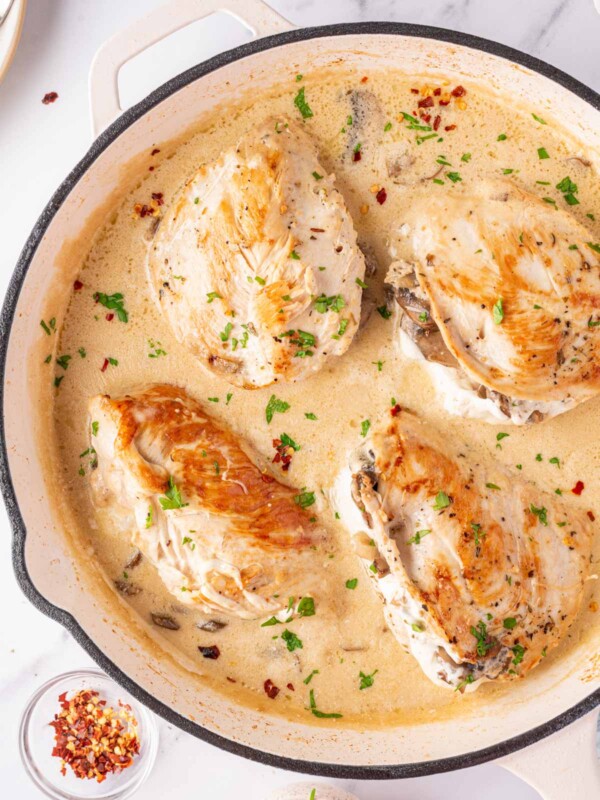 Mushroom Stuffed Chicken Breast in a white skillet with a creamy sauce..