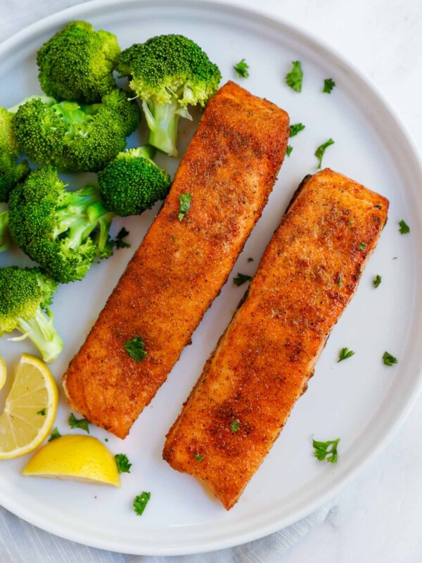 two pieces of air fried salmon on a plate with broccoli