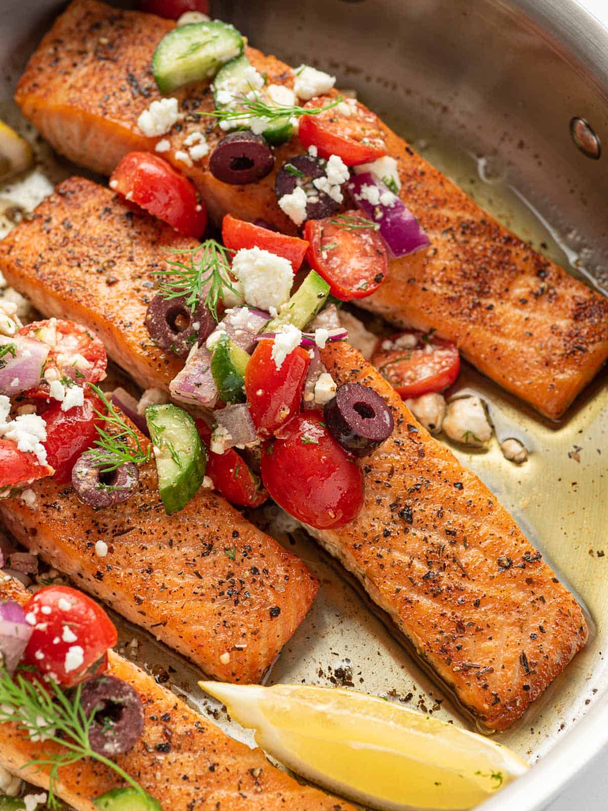 close up shot of greek salmon recipe in a skillet.