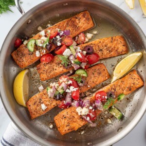 A skillet with grilled greek salmon and salsa.