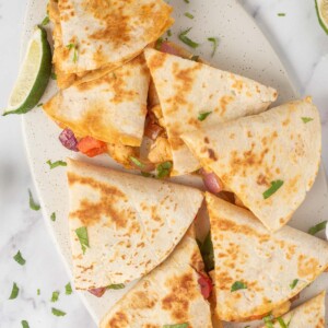 A platter of fajita quesadillas with a lime wedge.