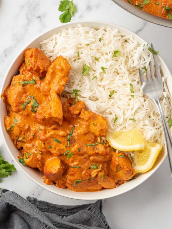 A fork rests on a bowl of healthy chicken tikka masala served with rice.