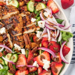 A serving platter with strawberry goat cheese salad and grilled chicken with balsamic dressing.