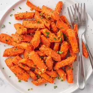 roasted carrots with parmesan cheese on a plate with two forks.
