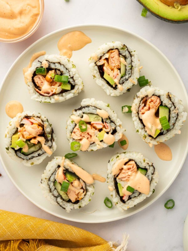Pieces of spicy salmon sushi roll rest on a plate.