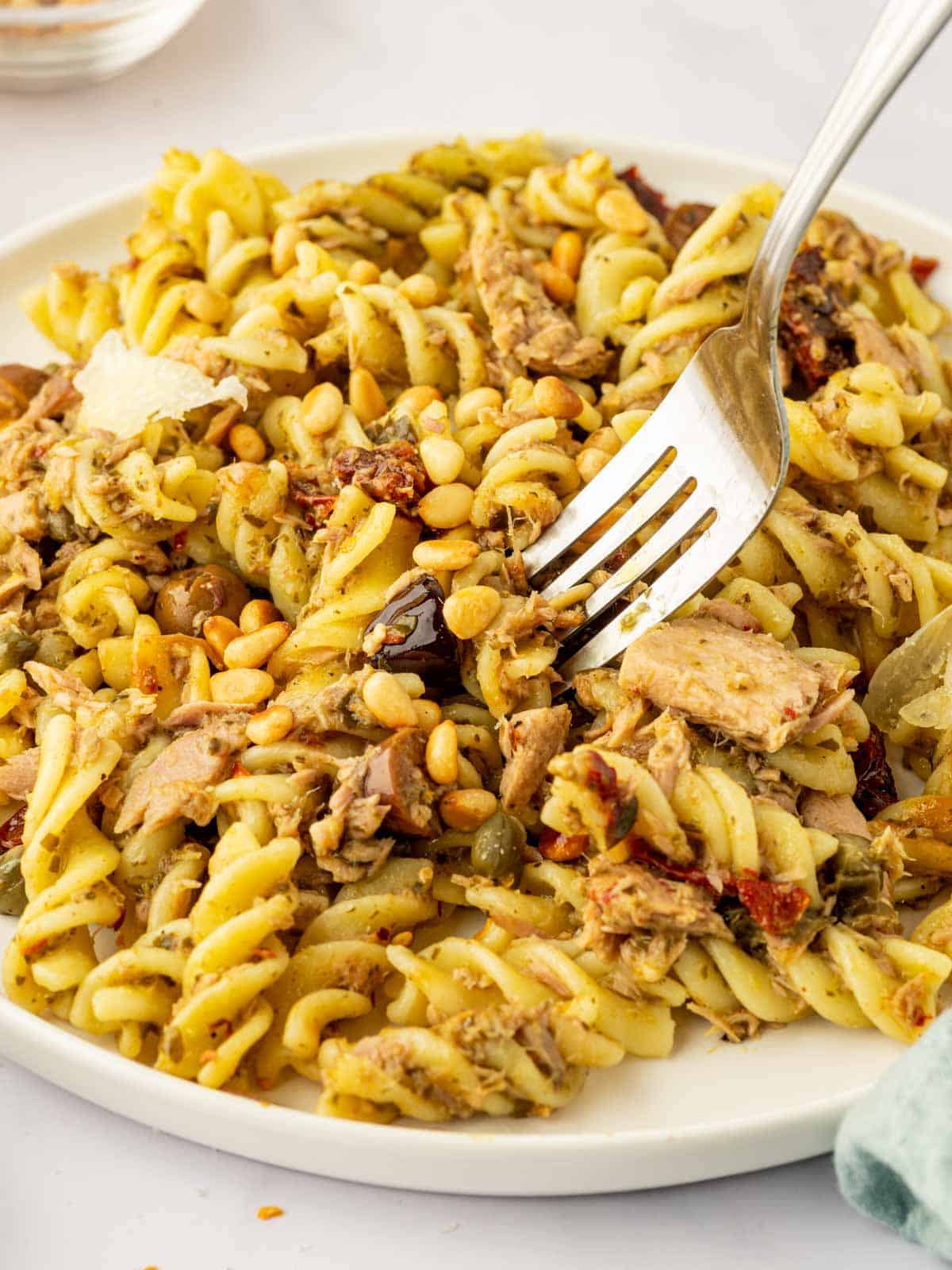 A fork pick up a bite of tuna pasta.