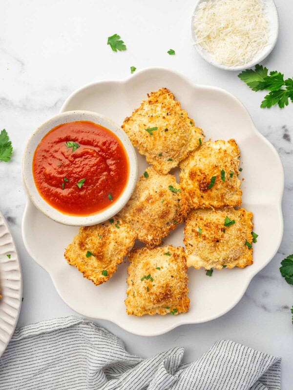 A platter of air fried ravioli with marinara sauce for dipping.