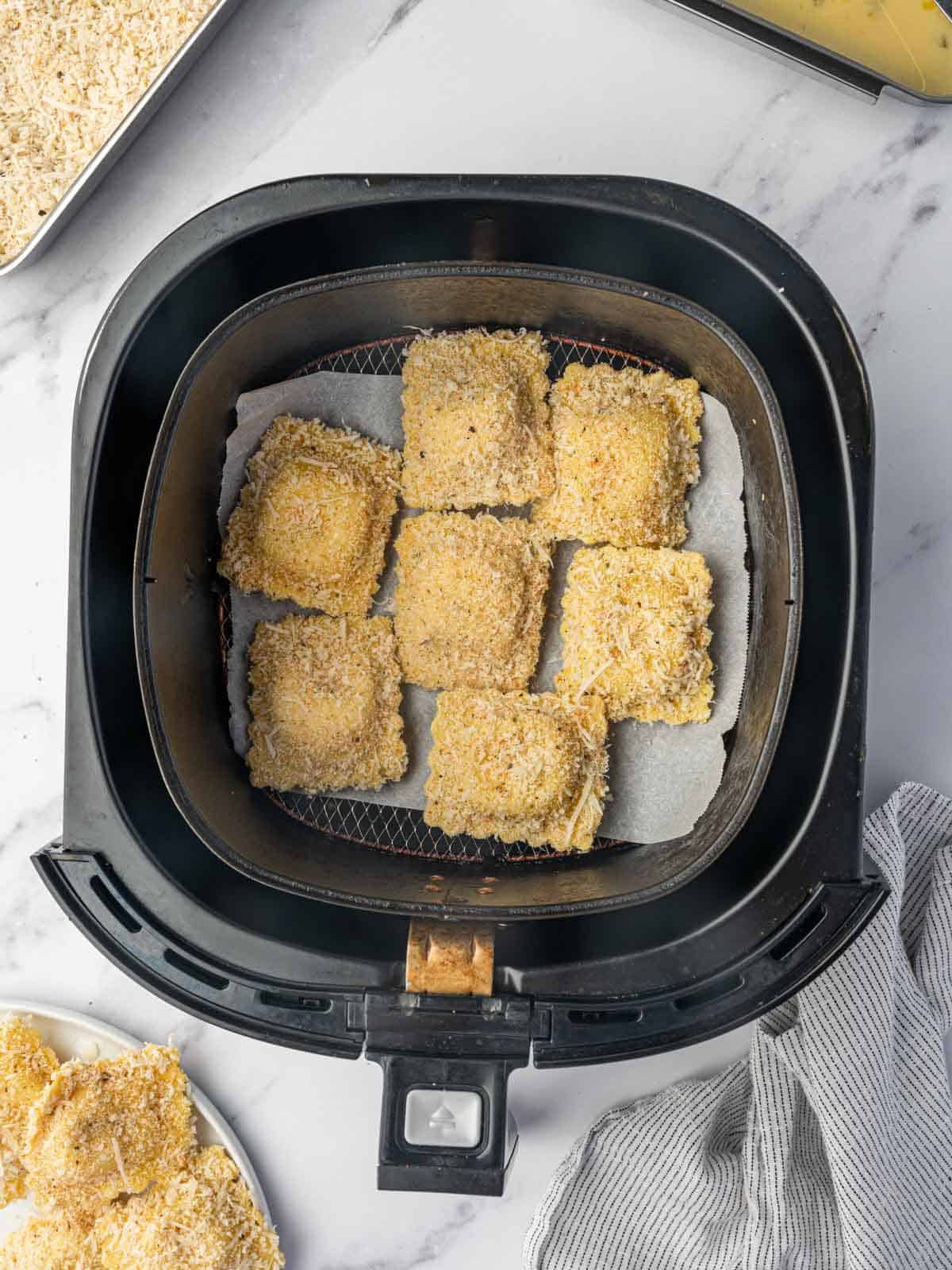 Breaded ravioli are in the air fryer basket in a single layer.