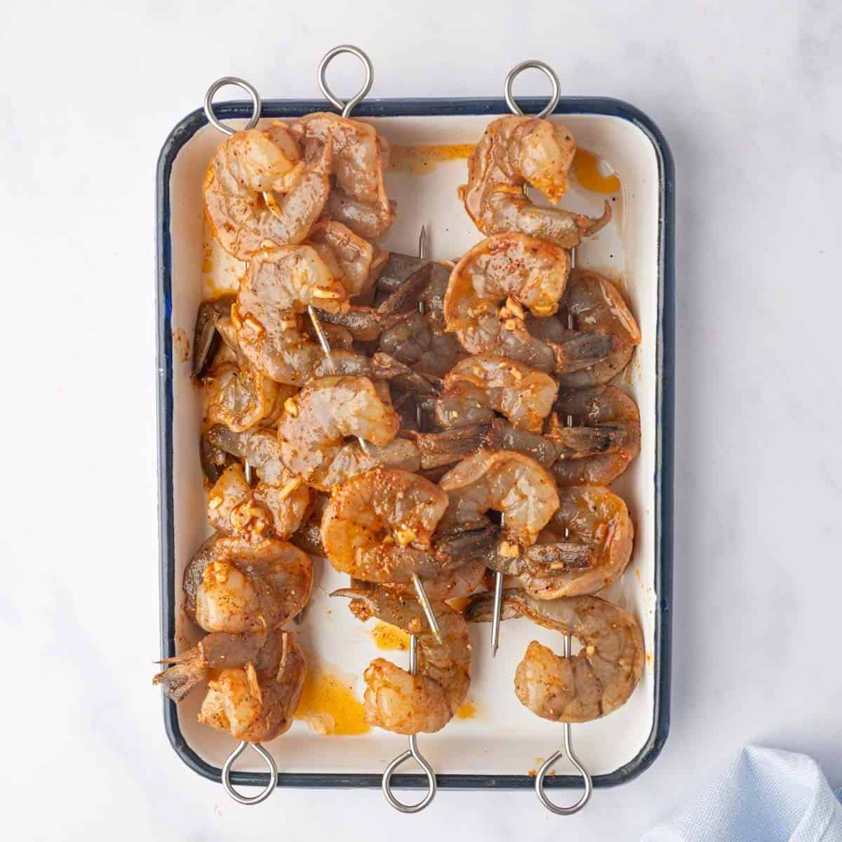 Marinated shrimp are threaded onto skewers.