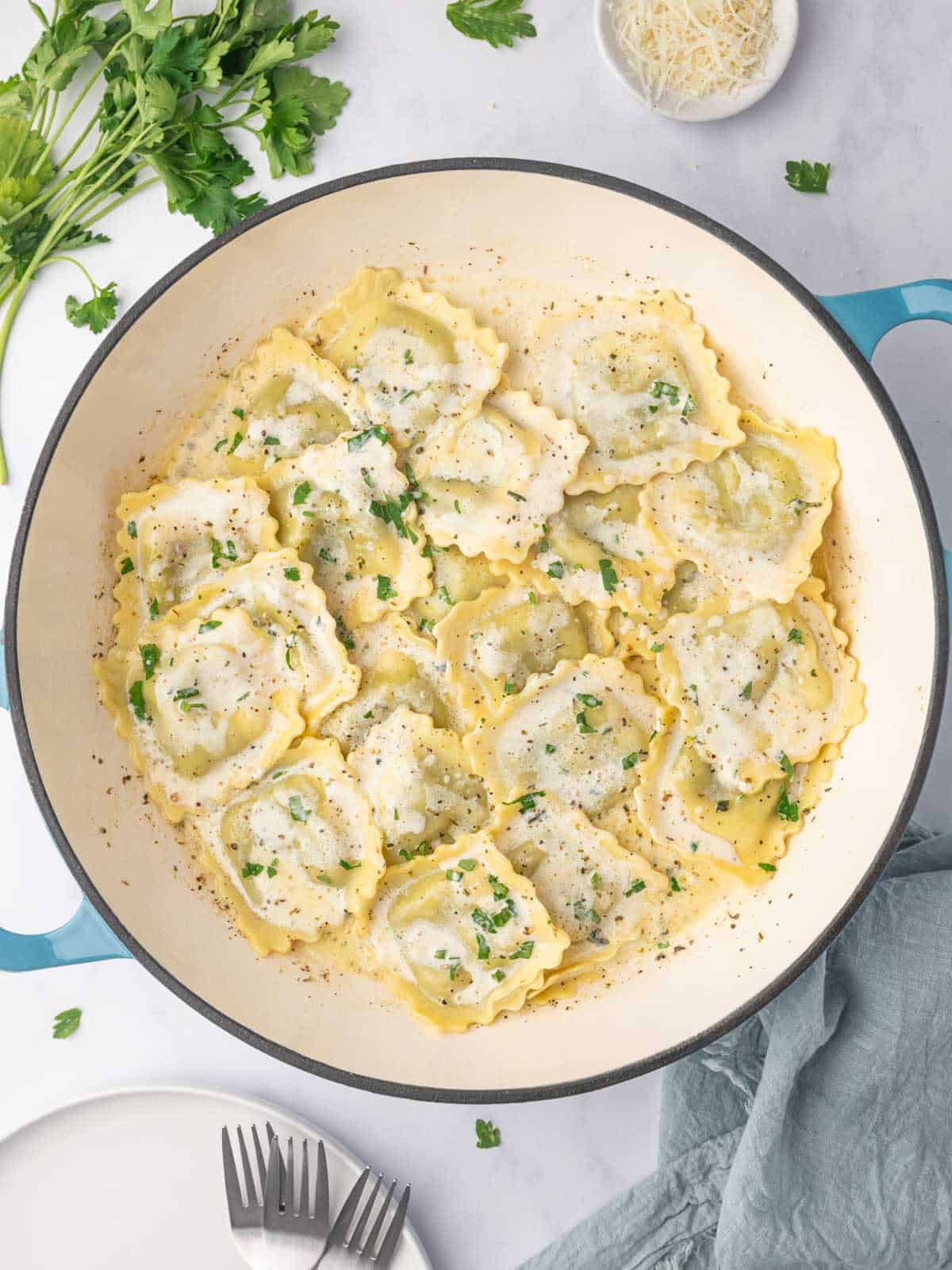 Spinach and ricotta ravioli with cream sauce in a dutch oven.