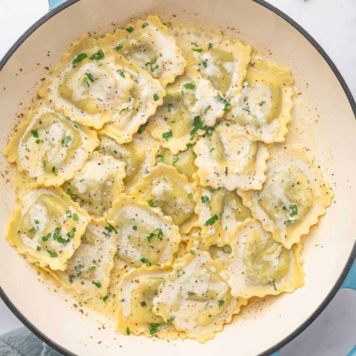 A dutch oven with spinach and cheese ravioli.
