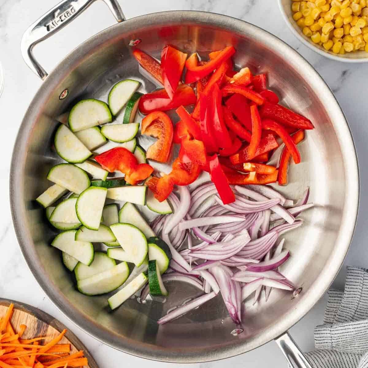 Chopped vegetables are added to a skillet to saute.