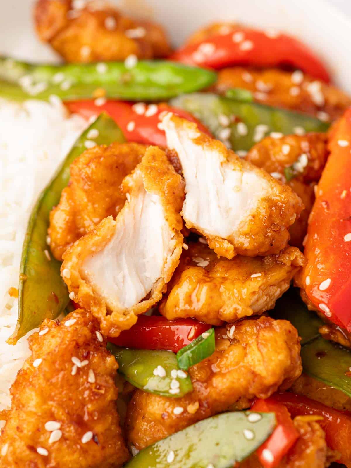 Closeup shot of a piece of crispy honey chili chicken cut in half.