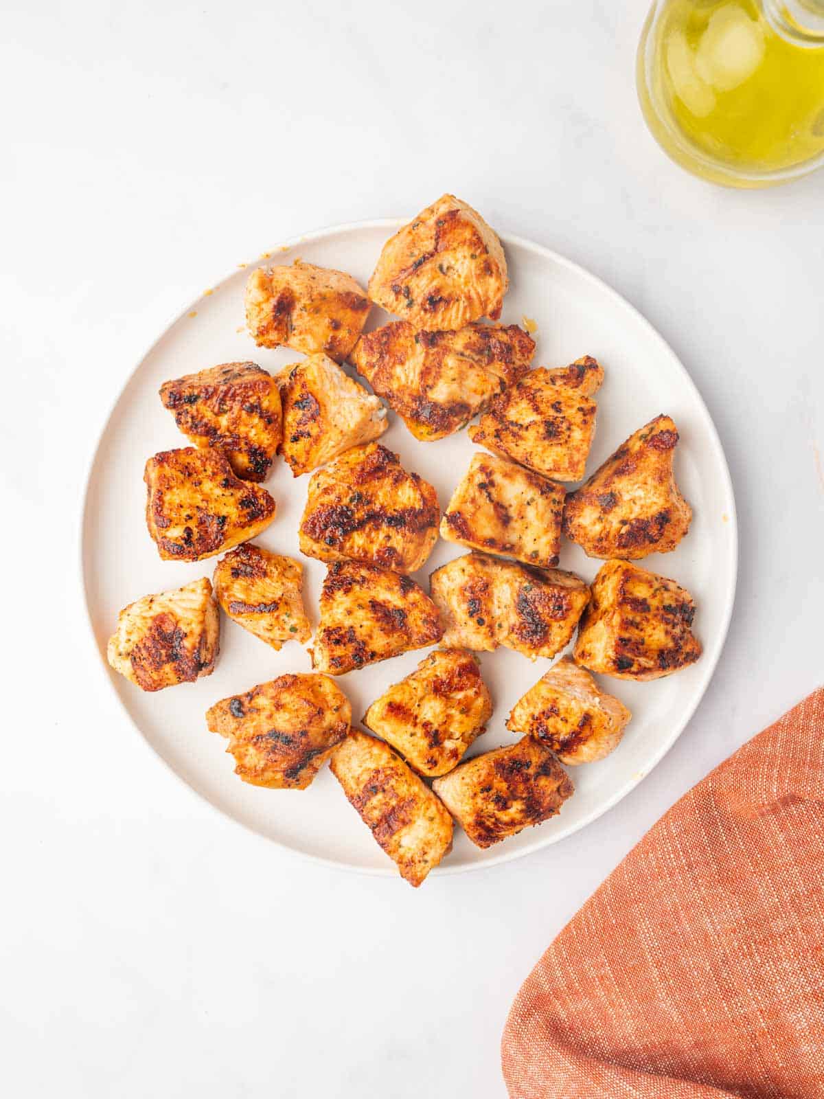 Grilled nuggets of chicken on a white plate.