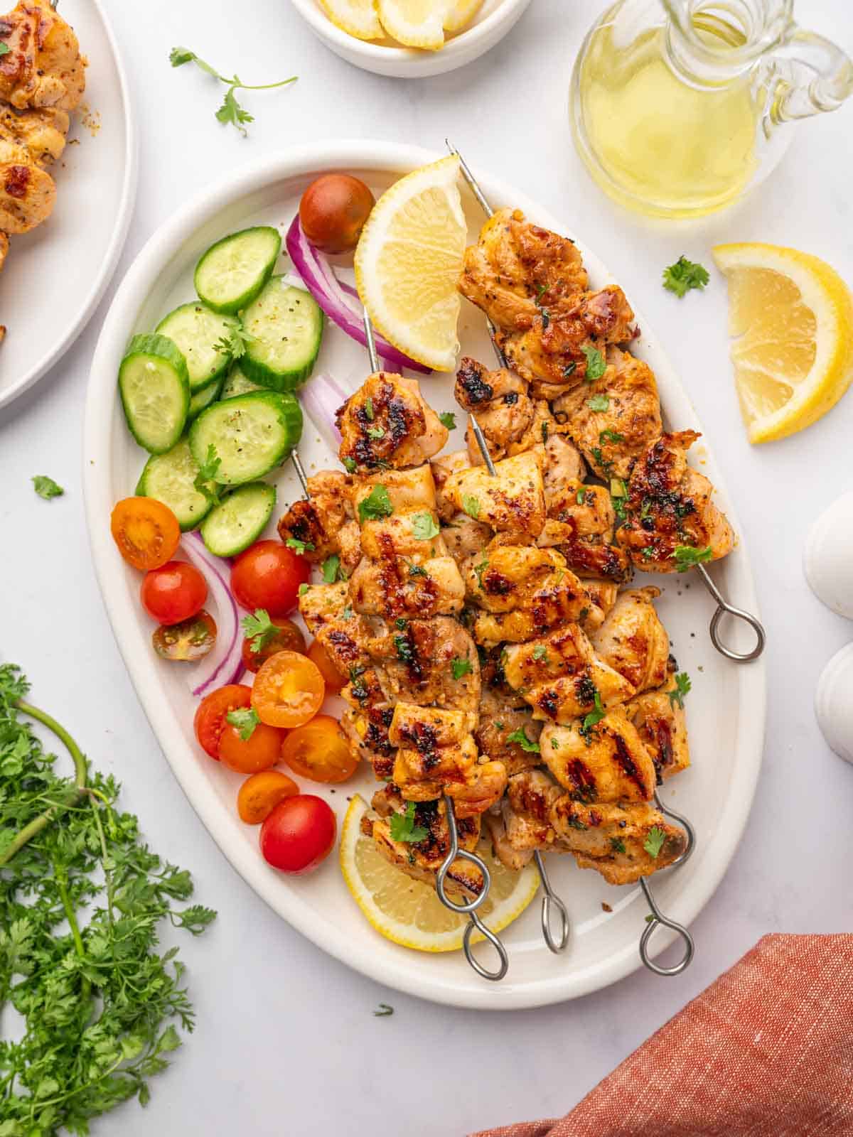 Grilled chicken with vegetables and lemon slices on a platter.