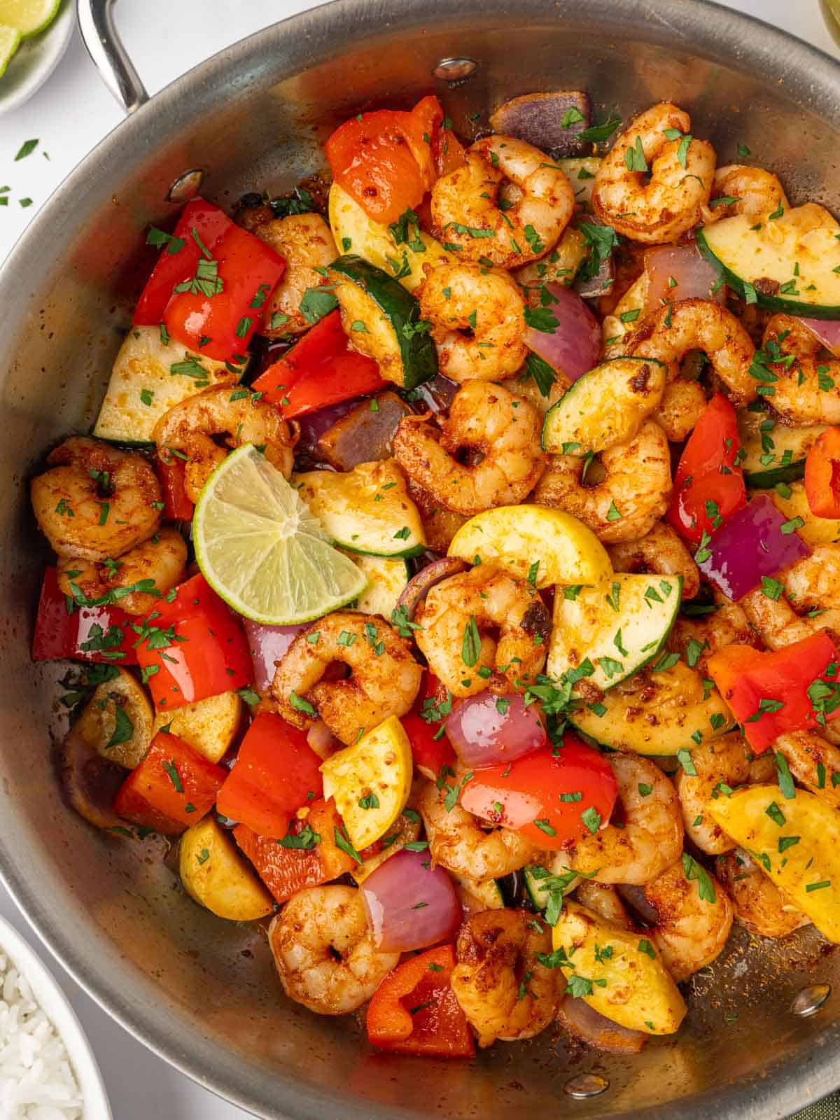 close-up of a skillet filled with sautéed shrimp and fresh vegetables.