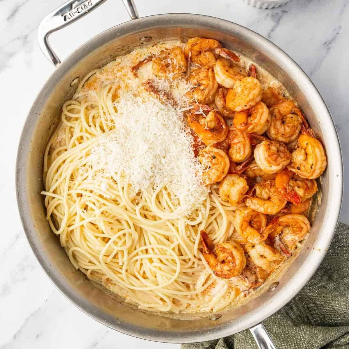 Combining cajun shrimp with pasta and parmesan in a skillet.